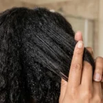 Woman testing hair porosity by spraying water onto a clean section of hair.