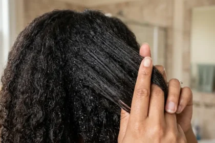Woman testing hair porosity by spraying water onto a clean section of hair.
