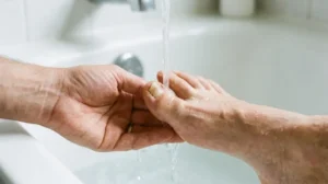 Person gently rinsing a loose big toenail with clean running water.
