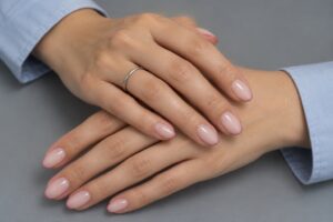 Nude pink almond nails with thin dusty rose micro French tips, paired with powder-blue sleeves.