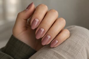Dusty rose almond nails with nude half-moons at the cuticles, paired with an olive sleeve and beige linen.