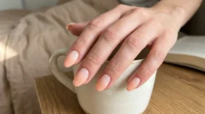 Close-up of soft peach ombré nails fading from nude to peach