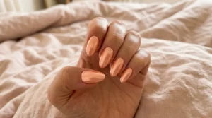 Close-up of soft peach chrome nails with a luminous metallic finish