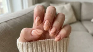 Close-up of peach and nude swirl nails with a soft glossy finish