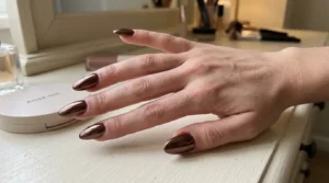 Close-up of classic chocolate brown chrome nails with a glossy reflective finish