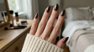Close-up of dark espresso brown chrome nails with a reflective finish