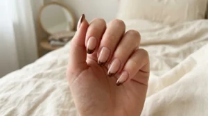 Close-up of brown chrome French tip nails on a nude base
