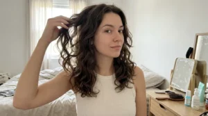 Young woman gently lifting her naturally loose hair during a relaxed hair-care routine