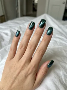 Forest green cat-eye nails viewed from an angle to show the changing magnetic shimmer