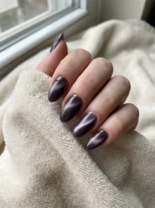 Plum cat-eye nails showing a magnetic stripe spreading across the glossy polish