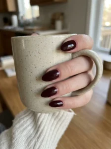 Glossy black cherry almond nails on a natural-looking hand