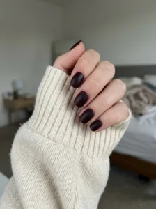 Matte black cherry burgundy nails on a natural-looking hand