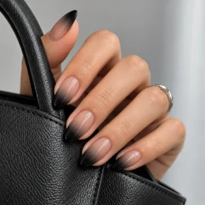 Smoky black ombré almond nails on a hand holding a black leather handbag.