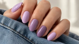 Glossy lilac and soft purple oval nails against blue denim.