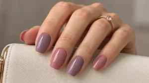 Glossy mauve and dusty rose nails on a hand resting over an ivory clutch.