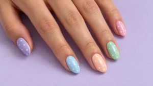 Pastel lilac, blue, peach, mint, and pink nails with tiny white polka dots.