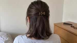 Back view of a simple half-up hairstyle secured with a tortoiseshell clip.