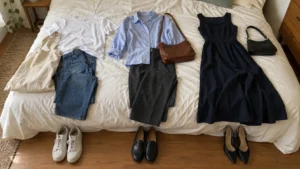 Three outfits arranged on a bed with matching bags and shoes for casual wear, work, and dinner.