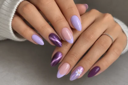 Purple nails almond manicure featuring lilac polish, French tips, violet cat eye shimmer, and a white flower accent