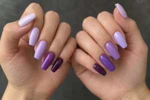 Two hands with coffin nails painted in purple shades ranging from pale lavender to deep plum.