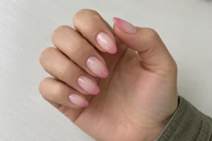 Close-up of almond nails with sheer nude bases fading into dusty rose tips and an olive sleeve.