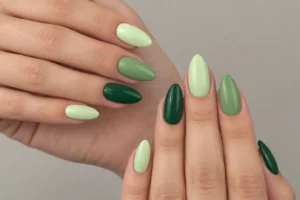 Close-up of two hands with glossy almond nails in pale pistachio, leafy green, and deep forest green shades.
