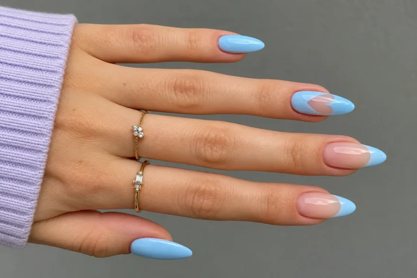 Spring manicure with pastel blue almond nails, blue French tips, nude accents, and delicate gold rings.