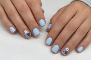 Soft blue short square nails with white, pale blue, and navy flowers on sheer accent nails.