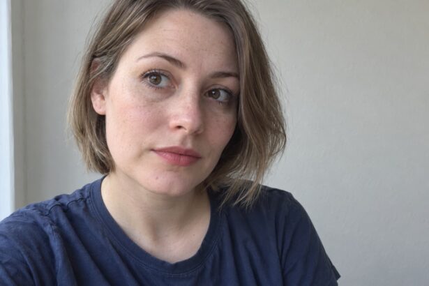 Fair-skinned woman with light everyday makeup and natural skin texture beside a window.