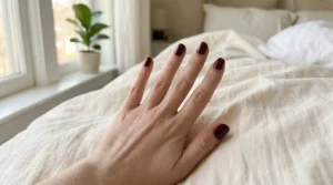 Short nails painted in a deep glossy oxblood burgundy shade