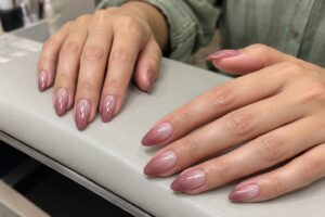 Almond nails with a blush-to-dusty-rose ombré and subtle shimmer, paired with sage green sleeves