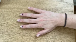 Minimal nude nails with small burgundy dot accents
