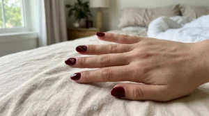 Glossy burgundy nails with delicate gold accent details